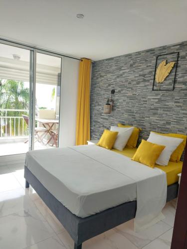 ein Schlafzimmer mit einem großen Bett mit gelben Kissen in der Unterkunft STUDIO Feuilles d'or in La Trinité