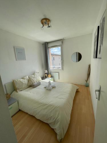 een groot wit bed in een kamer met een raam bij Appart'Bohème *CLIM*PARKING*WIFI*CONFORT in Blagnac