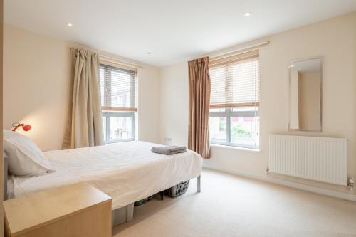een slaapkamer met een groot bed en 2 ramen bij 2 BR flat next to Train Station & Gated Parking in Cambridge