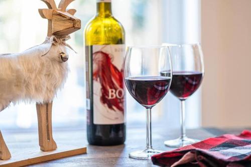 a bottle of wine and two wine glasses on a table at Le Grand Duc- SPA- Kayaks- bord Rivière Noire- VTT- Motoneige- Randonnée in Saint Come