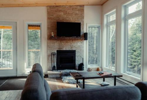 a living room with a couch and a fireplace at Le Grand Duc- SPA- Kayaks- bord Rivière Noire- VTT- Motoneige- Randonnée in Saint Come
