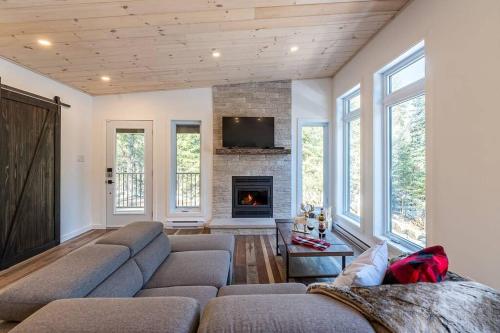 a living room with a couch and a fireplace at Le Grand Duc- SPA- Kayaks- bord Rivière Noire- VTT- Motoneige- Randonnée in Saint Come