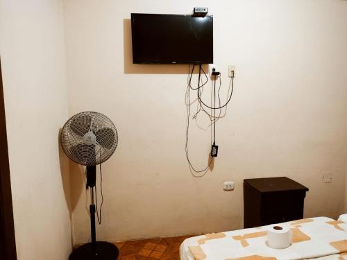 Habitación con ventilador y TV en la pared. en Hostal Muchik, en Chiclayo