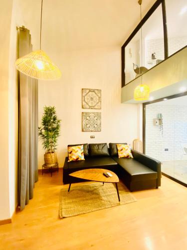 a living room with a black couch and a table at SUITE SORPRESA VuT LA TABERNA in Arenas de San Pedro