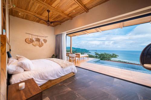 um quarto com uma cama e vista para o oceano em LALOON Luxury Suites - Adults Only em Santa Teresa