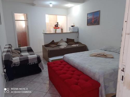 1 dormitorio con 2 camas y reposapiés rojo en STUDIO Centro Lacerda, en Campos dos Goytacazes