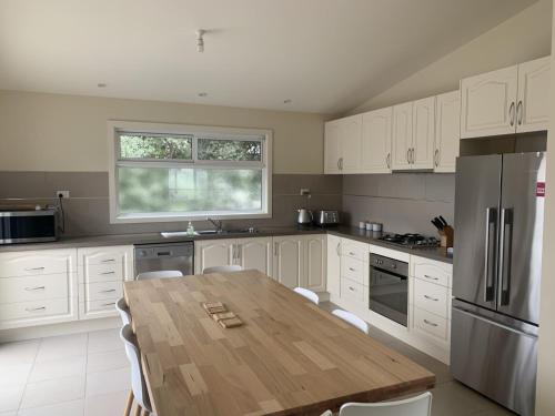 a kitchen with a wooden table and a refrigerator at Contemporary On Cuttriss Inlet Side in Inverloch