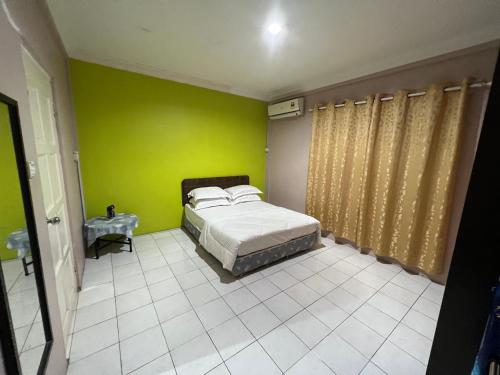 a bedroom with a bed and a green wall at Hanif Homestay in Kuching
