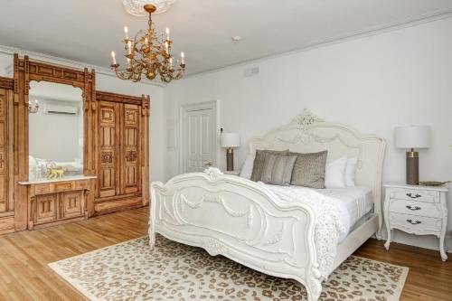 a white bedroom with a white bed and a chandelier at The Peninsula in Cape May Court House