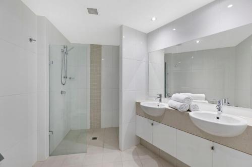 a white bathroom with two sinks and a shower at Coast Luxury Apartment 3 in The Entrance