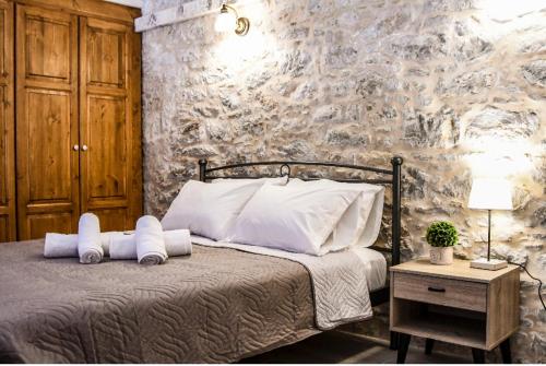 a bedroom with a bed with pillows and a stone wall at Stone Living Symi Central Apartments in Symi