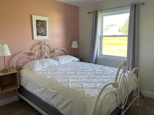 a bedroom with a white bed with a window at Gateway to Greenwich Suites in Saint Peters