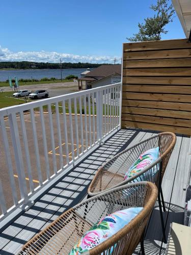 a balcony with a chair and a fence and water at Gateway to Greenwich Suites in Saint Peters