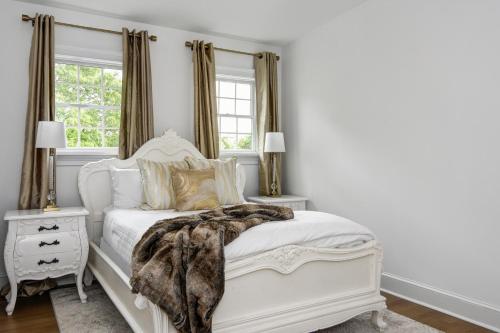a bedroom with a white bed with a blanket on it at The Peninsula in Cape May Court House
