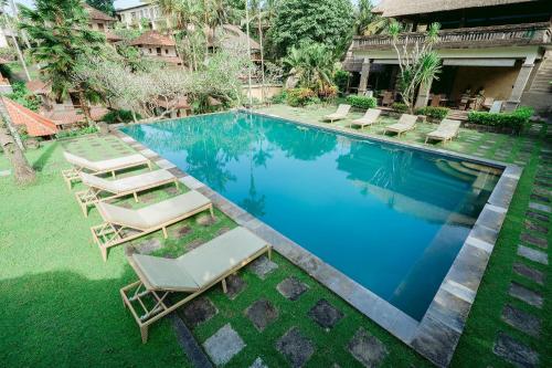 a pool with chaise lounge chairs and a resort at Pertiwi Resort & Spa in Ubud