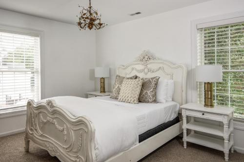 a white bedroom with a white bed and two windows at The Peninsula in Cape May Court House
