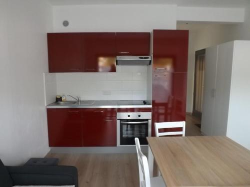 une cuisine avec des placards rouges et une table en bois dans l'établissement Appartement T2 en RDC, Proche Plage et Commerces, Idéal pour Séjours en Bord de Mer - FR-1-646-30, à Berck-sur-Mer