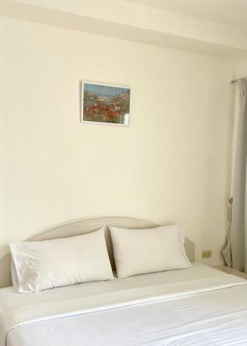 a bed with white pillows and a painting on the wall at โรงแรมเอสซีเรสซิเดนซ์ มุกดาหาร in Mukdahan