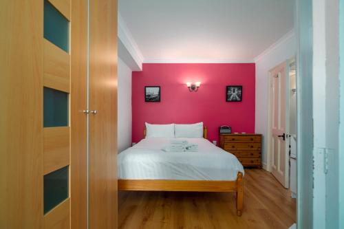 a bedroom with a pink wall and a bed at Fantastic 1 bedroom apartment with private patio in London