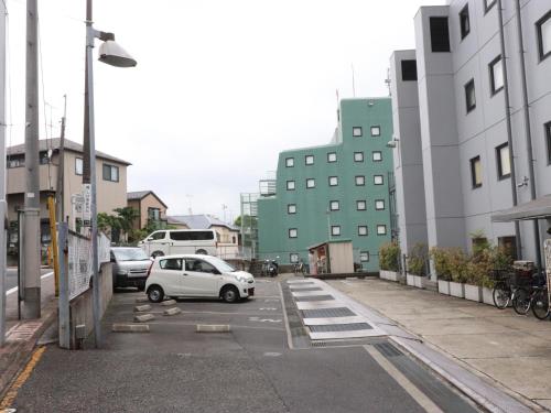 a white car parked in a parking lot next to buildings at Tokyo Inn in Tokyo
