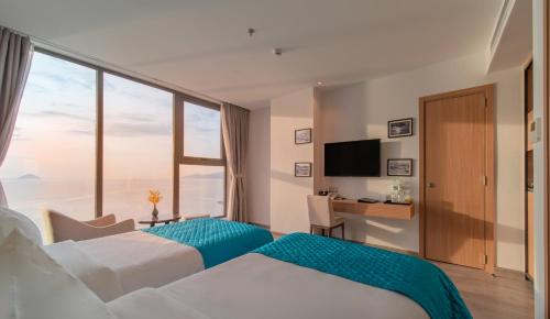 a hotel room with two beds and a large window at Navada Beach Hotel in Nha Trang