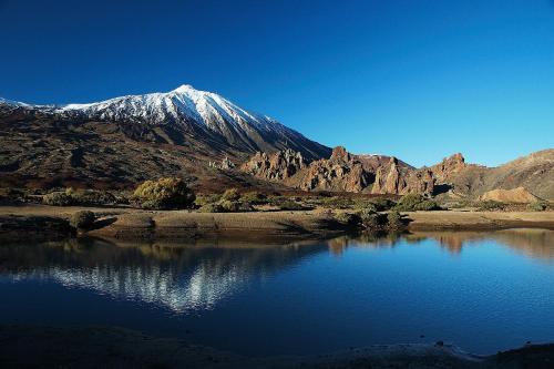 a snow covered mountain sitting next to a body of water at Hotel Monopol in Puerto de la Cruz