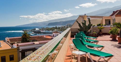 a row of green chairs on a balcony overlooking the ocean at Hotel Monopol in Puerto de la Cruz
