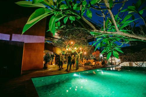a group of people standing by a swimming pool at night at Pertiwi Resort & Spa in Ubud