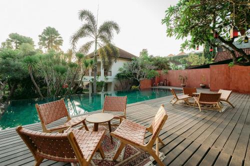 a deck with chairs and a table next to a pool at Pertiwi Resort & Spa in Ubud