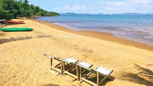 a beach with two lounge chairs and a green canoe at Sunflower Villas in Ko Chang