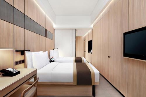a hotel room with a bed and a flat screen tv at Harbour Plaza Metropolitan Shanghai in Shanghai