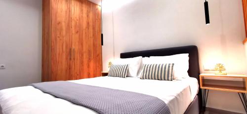 1 dormitorio con cama blanca y cabecero de madera en Urban Luxus Studio II en Heraclión