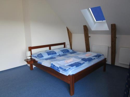 a bedroom with a bed with blue sheets and a window at Penzion Alma in Znojmo