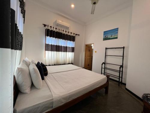 um quarto com uma cama com lençóis brancos e almofadas em Lahiru Villa em Galle