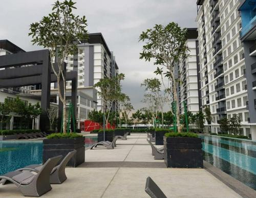 a courtyard with a pool and chairs and buildings at BSP21 Family Homestay in Jenjarum
