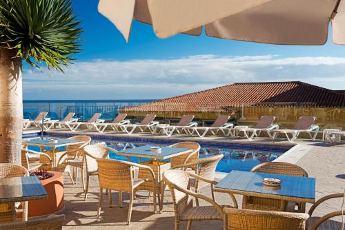 a patio with tables and chairs and a swimming pool at Hotel Monopol in Puerto de la Cruz