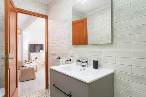 Un baño blanco con lavabo y espejo. en Apartamento Can Marce, en Cala de Sant Vicent