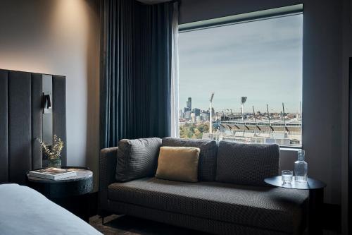 a living room with a couch in front of a window at Pullman Melbourne On the Park in Melbourne