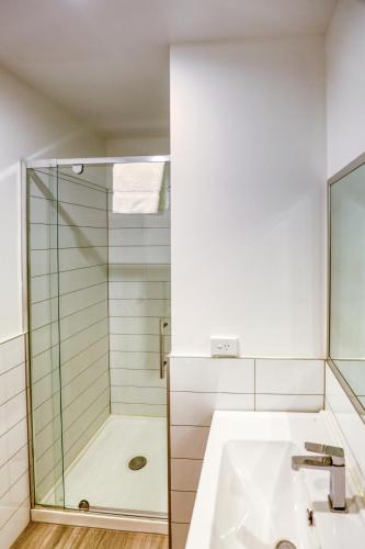 a bathroom with a glass shower and a sink at Ramada Suites By Wyndham Victoria Street West in Auckland