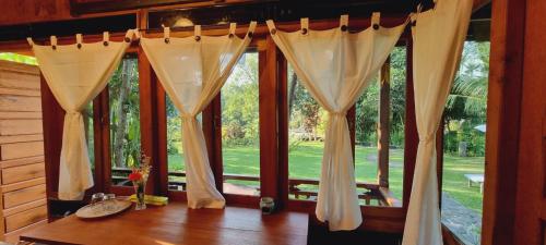 a room with windows with curtains and a table at Avalon Ubud Castle & SPA in Ubud
