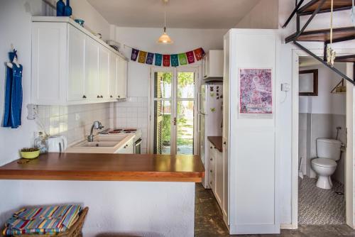 a kitchen with white cabinets and a sink and a toilet at Mola Home by halu! Villas in Mola Kalyva