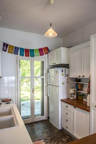 a kitchen with white cabinets and a white refrigerator at Mola Home by halu! Villas in Mola Kalyva