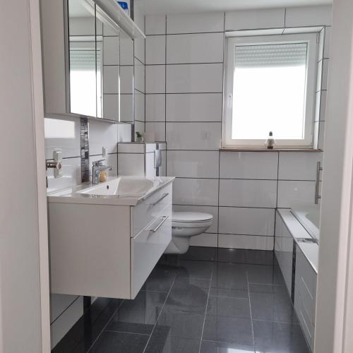 a bathroom with a sink and a toilet and a window at Ferienwohnung am Kupferbach in Wolfterode
