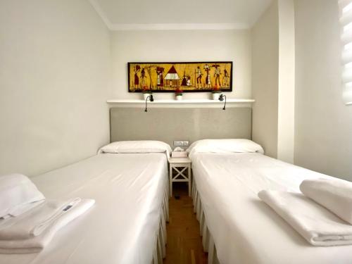 - 2 lits dans une chambre avec une table dans l'établissement Housingleón - Tu casa en León, à León