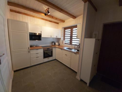 eine Küche mit weißen Schränken, einer Spüle und einem Kühlschrank in der Unterkunft Domek Żeglarza in Borsk