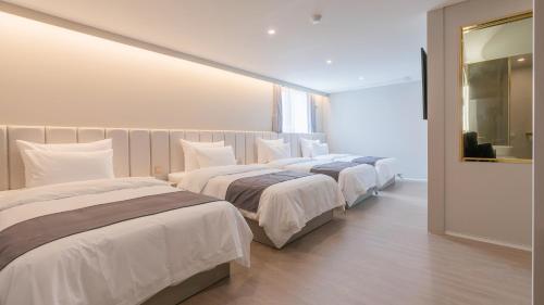 a bedroom with two beds and a mirror at Denbasta Central Hotel Seomyeon in Busan