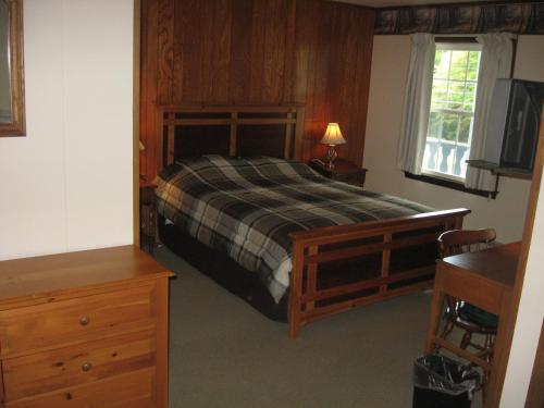 a bedroom with a bed and a dresser and a window at Big Bears Lodge in West Dover