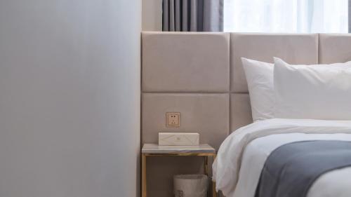 a bed with a clock on a night stand next to a bed at Denbasta Central Hotel Seomyeon in Busan