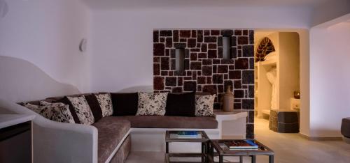 a living room with a couch and a brick wall at Acro Blue Luxury Villas in Akrotiri