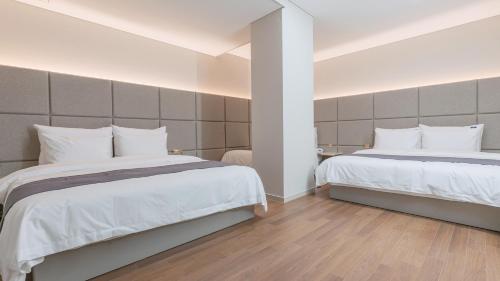a bedroom with two beds with white sheets at Denbasta Central Hotel Seomyeon in Busan
